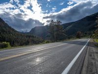 a person on a bike rides down the road with mountains in the distance along side of it