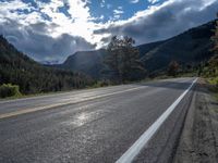 a person on a bike rides down the road with mountains in the distance along side of it