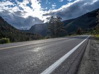 a person on a bike rides down the road with mountains in the distance along side of it