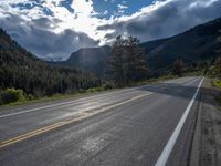 a person on a bike rides down the road with mountains in the distance along side of it