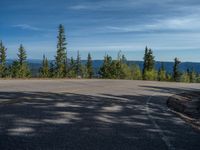 the mountains are visible in the distance from this wide, empty road, overlooking a wide landscape and forest