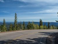 the mountains are visible in the distance from this wide, empty road, overlooking a wide landscape and forest