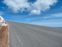 a man is riding his bike down a mountain road with snow and rocks in the background