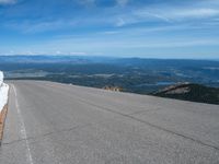 a snow covered road is near a very steep cliff on a clear day the wall is filled with snow and snow