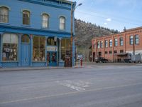 a red fire hydrant sitting in front of an old store window and building next to an open air field