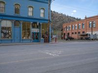 a red fire hydrant sitting in front of an old store window and building next to an open air field