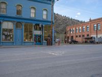 a red fire hydrant sitting in front of an old store window and building next to an open air field