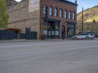 a red fire hydrant sitting in front of an old store window and building next to an open air field