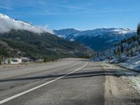 a snowy road lined up with snow and mountains in the background in the wilderness area