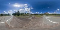 multiple train tracks are shown in a fish eye view lens with clouds and a mountain in the background