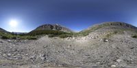 a panorama of some very large mountains in the country side by side with rocks and brush