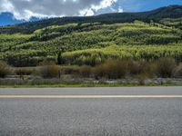 the road is paved with yellow markings and has a snowy mountain range in the background