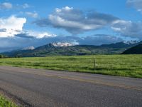 a lone country road is in the countryside area with mountains on both sides and barbed fence between the two sides