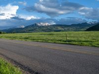 a lone country road is in the countryside area with mountains on both sides and barbed fence between the two sides