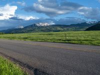 a lone country road is in the countryside area with mountains on both sides and barbed fence between the two sides