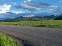a lone country road is in the countryside area with mountains on both sides and barbed fence between the two sides