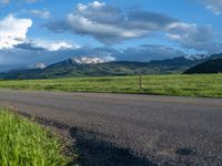 a lone country road is in the countryside area with mountains on both sides and barbed fence between the two sides