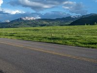 a lone country road is in the countryside area with mountains on both sides and barbed fence between the two sides