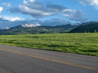 a lone country road is in the countryside area with mountains on both sides and barbed fence between the two sides