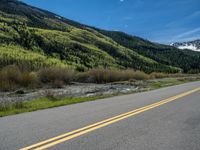 the road is paved with yellow markings and has a snowy mountain range in the background