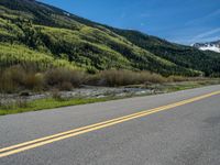 the road is paved with yellow markings and has a snowy mountain range in the background