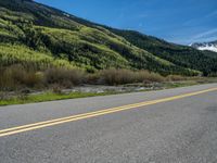 the road is paved with yellow markings and has a snowy mountain range in the background