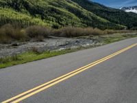 the road is paved with yellow markings and has a snowy mountain range in the background