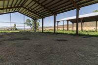 the inside of an empty barn with hay around and on the floor is a big open air shelter