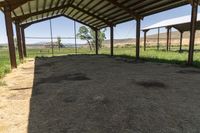 the inside of an empty barn with hay around and on the floor is a big open air shelter