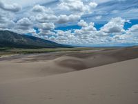 a person riding down a mountain side on a horse in the sand of a flat plain