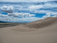 the sand hills are very tall and the clouds are beautiful in the sky over it