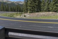 the road near the mountains has yellow lines on it and a line in the middle of the road