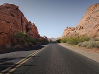 the road in the valley of fire, with a few rocks surrounding it with grass and shrubs