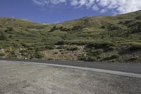 the empty mountain road has a curve sign along it and there is a sky background with wispy clouds