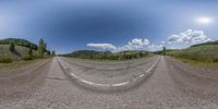 an image of a road in the middle of nowhere and empty field area with the sun in the sky and clouds