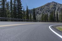 the curves of an empty road in front of a rocky mountain range in the area