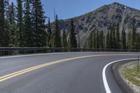 the curves of an empty road in front of a rocky mountain range in the area