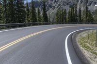 the curves of an empty road in front of a rocky mountain range in the area