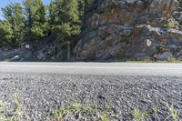 a large rock formation is on the side of the road in front of a graveled hillside