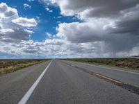 a lone highway winds down against an empty sky and clouds overhead as the view is clearly from a distance