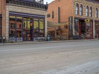 a red fire hydrant sitting in front of an old store window and building next to an open air field