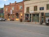 a red fire hydrant sitting in front of an old store window and building next to an open air field