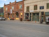 a red fire hydrant sitting in front of an old store window and building next to an open air field