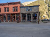 a red fire hydrant sitting in front of an old store window and building next to an open air field