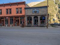 a red fire hydrant sitting in front of an old store window and building next to an open air field