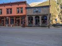 a red fire hydrant sitting in front of an old store window and building next to an open air field