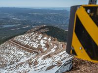 an empty road and a hill overlook the view of mountains and clouds and blue sky