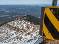 an empty road and a hill overlook the view of mountains and clouds and blue sky
