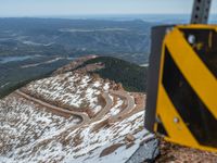 an empty road and a hill overlook the view of mountains and clouds and blue sky