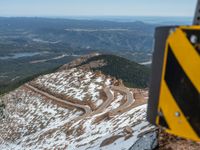 an empty road and a hill overlook the view of mountains and clouds and blue sky